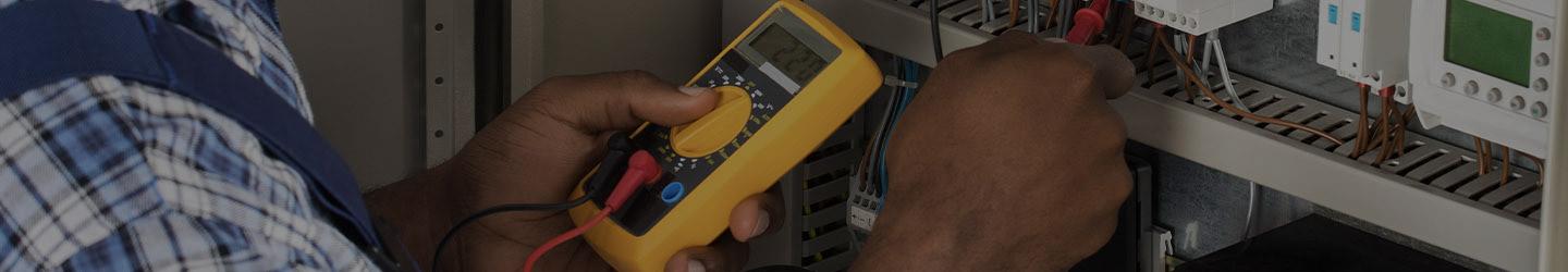 Electrician using a current meter on an electric panel