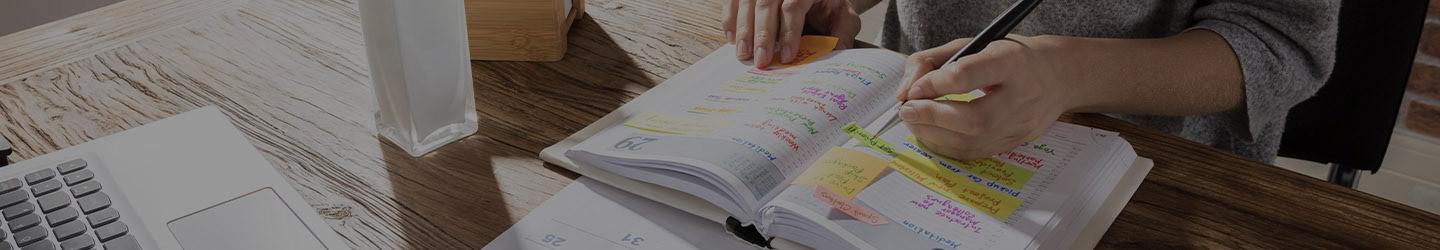 Woman taking notes on her planner at her desk