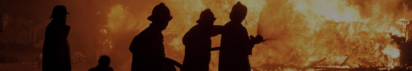 Silhouettes of firefighters putting out a fire at night