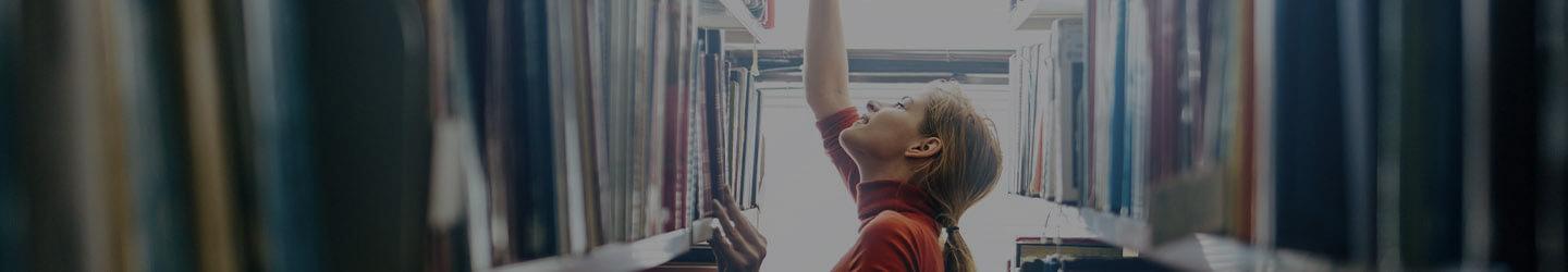 Librarian reaching for a book in a bookshelf