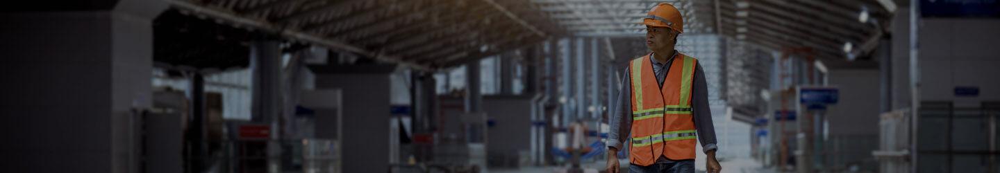 Engineer wearing a hardhat walking through a factory