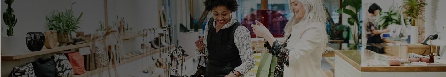 female retail worker helping female shopper with jewelry